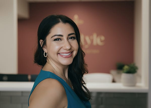 Smiling woman standing in front of a dental office reception area background